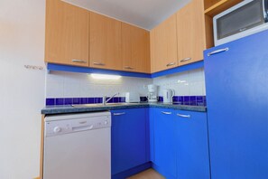 A compact kitchen with wooden cabinets, a built-in microwave, and a dishwasher.