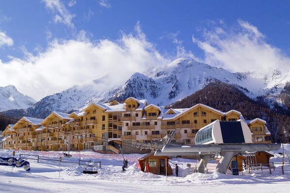 A snow-covered mountain resort with wooden buildings and a ski lift.