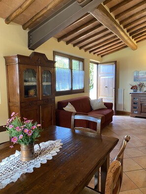 A cozy living room with a wooden dining table, a red sofa, and a wooden cabinet with glass doors.