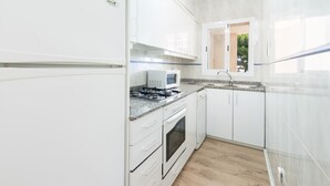 Eine moderne Küche mit weißen Schränken, einer Mikrowelle, einem Herd und einem Fenster.