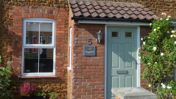 A two-story brick house with a light blue door, a small porch, and a sign that reads "Tuscany." - Fuzzy Duck Cottage. Over 100 5 star reviews on Trip Advisor. Sleeps 4  (Heacham)