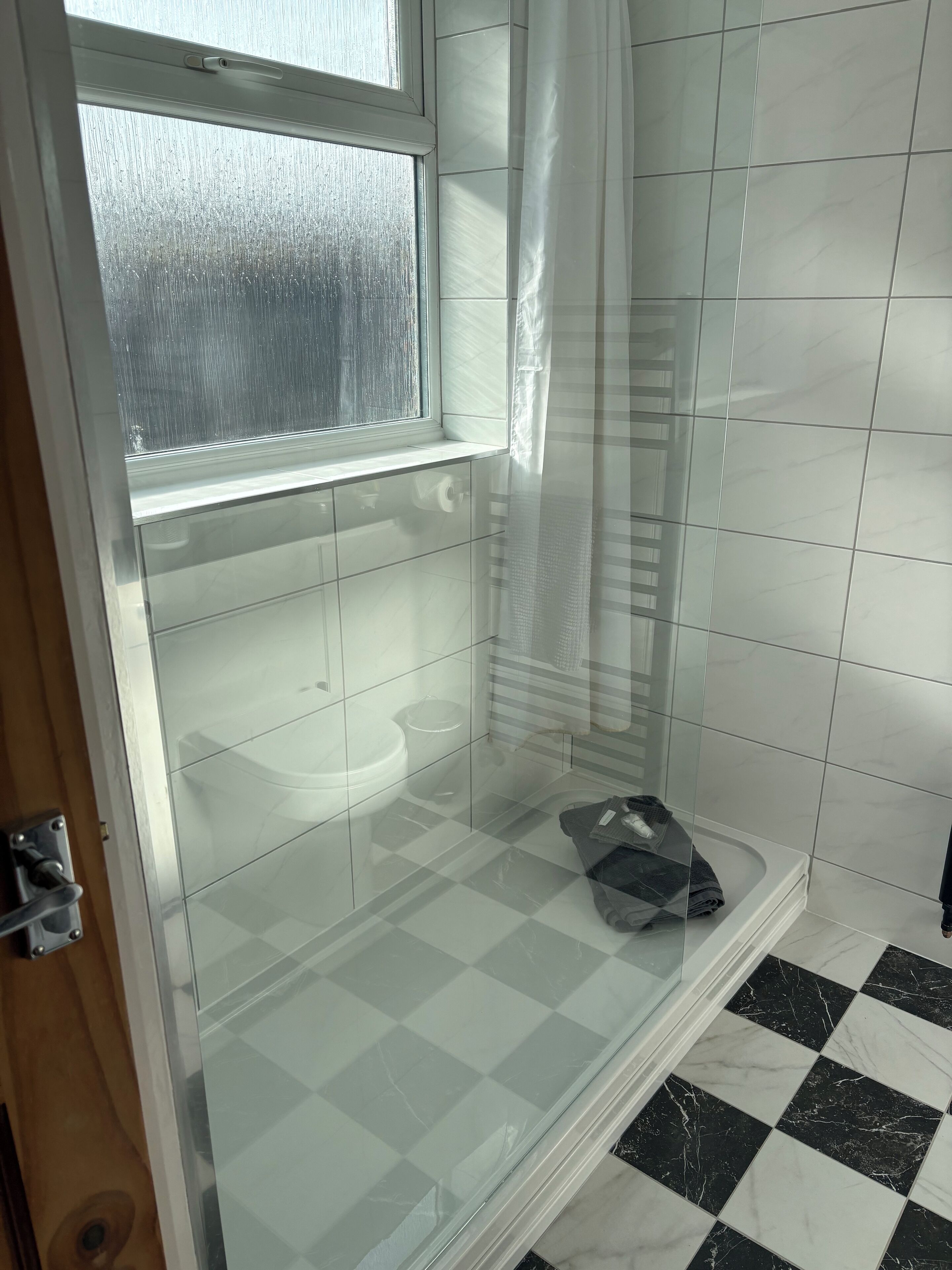 Une salle de bain avec une douche à parois de verre, des toilettes et un lavabo.