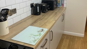 A kitchen with a wooden countertop, a stove, a sink, and a wall-mounted shelf with kitchenware. - Fuzzy Duck Cottage. Over 100 5 star reviews on Trip Advisor. Sleeps 4  (Heacham)