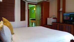 Una habitación de hotel con una cama, un televisor y una puerta verde que da a otra habitación.