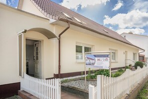 A residential property with a white exterior, a tiled roof, and a small garden area.
