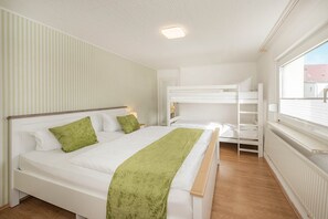 Una camera da letto con un letto a castello, un letto singolo e una finestra vista.