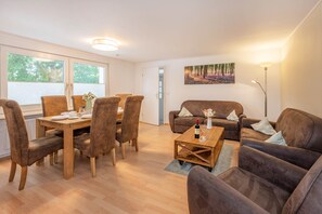 A furnished living room with a dining area, a sofa, a coffee table, and a painting on the wall.