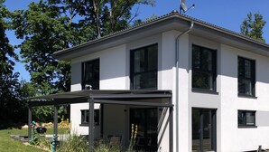 A modern two-story building with a covered porch, large windows, and a satellite dish.