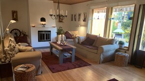 Un salon chaleureux avec une cheminée, des sièges confortables et une vue sur l’extérieur.