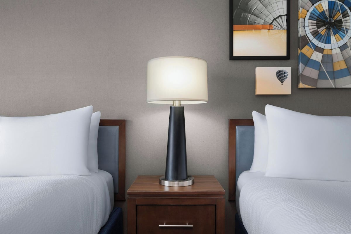 Ein Hotelzimmer mit zwei Betten, einem Nachttisch mit Lampe und einem Bild an der Wand.