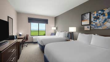 A hotel room with two beds, a desk, a TV, and a large window with a view.