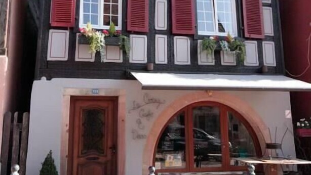 Un bâtiment traditionnel à colombages, doté d’une porte en bois et d’un petit balcon agrémenté de plantes.