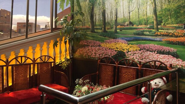 A room with a view of a garden through large windows, wicker furniture, and a red sofa. - Gran Copacabana Hostal (El Alto)