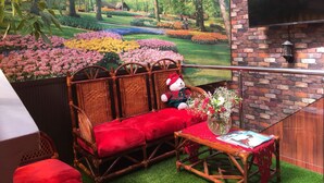 A cozy seating area with a wicker sofa, red cushions, and a small table with a vase of flowers. - Gran Copacabana Hostal (El Alto)