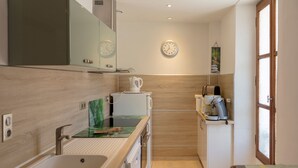 Una cocina moderna con pileta, encimera, estufa y cafetera.