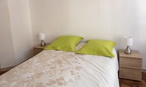 Une chambre à coucher avec un lit, deux tables de chevet et deux lampes.