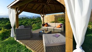 An outdoor seating area with wicker furniture and a wooden deck, overlooking a lush landscape. - Luxury villa 160 m2 with magnificent mountain view and HEATED SWIMMING POOL (Bois d'Olives)