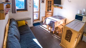 A cozy living area with a sofa, a dining table, and a kitchen area with a microwave.