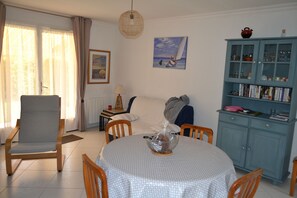 A dining area with a round table, chairs, a cabinet with glass doors, and a painting on the wall.