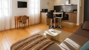 A modern living room with a sofa, a coffee table, and a dining area with chairs and a small kitchen. - Family Suite F3 Grant in the heart of Chartres has 55m2 2 bedrooms, parking (Chartres)