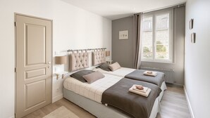 A bedroom with two beds, a radiator, a window with curtains, and a door. - Family Suite F3 Grant in the heart of Chartres has 55m2 2 bedrooms, parking (Chartres)