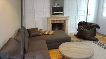 A living room with a sectional sofa, a round coffee table, a fireplace, and a mirror above it.