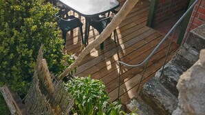Una terraza de madera con mesa y sillas, con vistas a un cuerpo de agua.