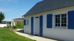 Un bâtiment blanc avec des volets bleus et une allée gravillonnée.