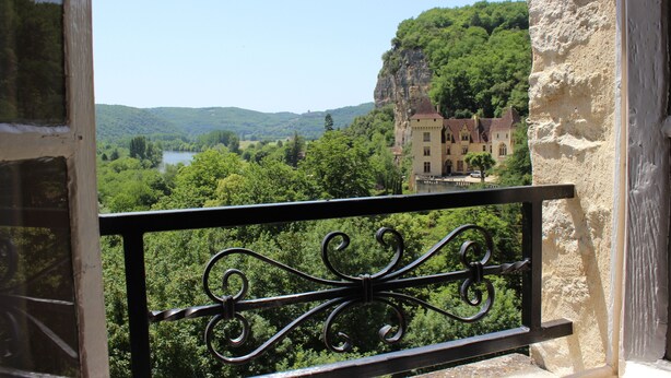 A balcony with a wrought iron railing overlooking a scenic landscape with a lake, forested hills, and a castle-like building in the distance. - Gabarier's house in the historic heart of the medieval village of La Roque Gageac (La Roque-Gageac)