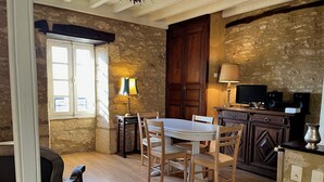 A cozy dining area with a wooden table and chairs, a stone wall, and a wooden door. - Gabarier's house in the historic heart of the medieval village of La Roque Gageac (La Roque-Gageac)
