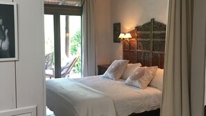 A bedroom with a bed, a ceiling fan, a nightstand with lamps, and a view of the outdoors.