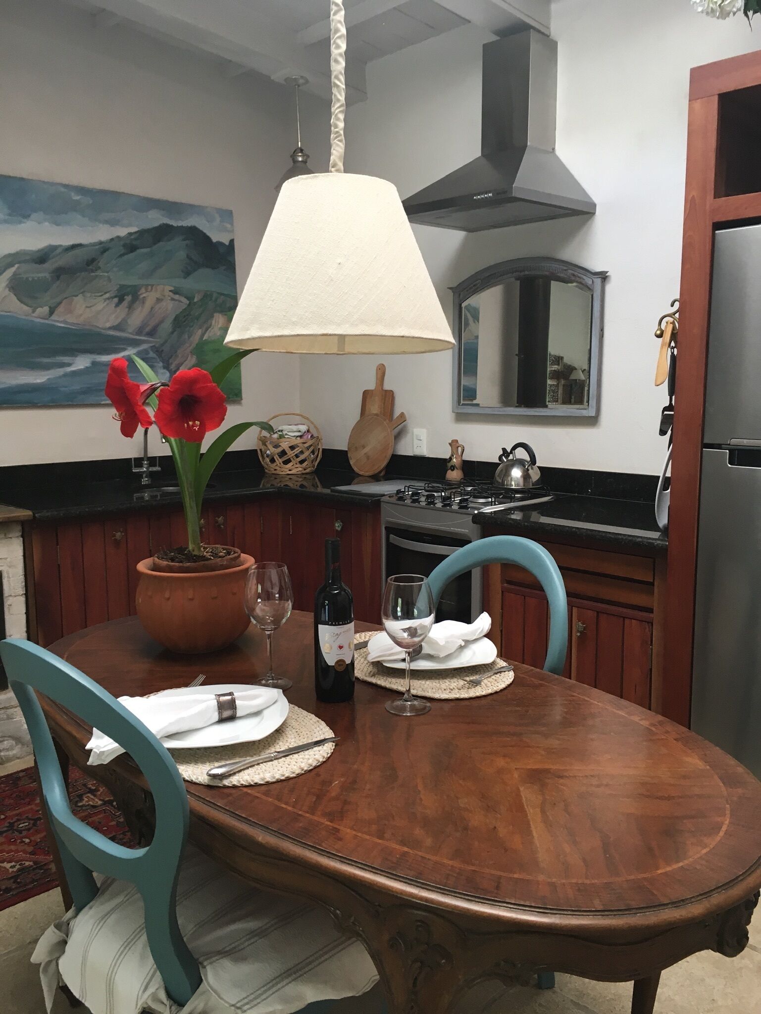Une table à manger avec des chaises, une plante en pot, une bouteille de vin et un verre à vin.