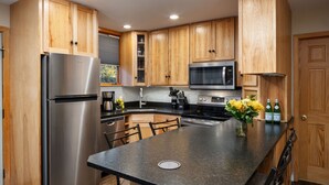 A modern kitchen with wooden cabinets, stainless steel appliances, a granite countertop, and a central island with seating.