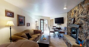 A living room with a sofa, a coffee table, a fireplace, and a television.