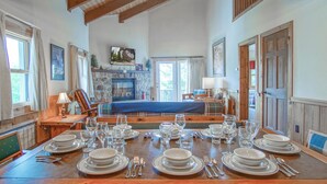 A dining area with a wooden table set for a meal, a fireplace, and a view of the outdoors. - Whistlepunk #12:  4 Bedroom, 3 Bath:  Slope Side, Wood Fireplace. (Snowshoe)