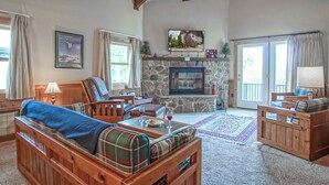 A cozy living room with a stone fireplace, wooden furniture, and a television mounted above it. - Whistlepunk #12:  4 Bedroom, 3 Bath:  Slope Side, Wood Fireplace. (Snowshoe)