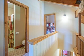 A staircase with wooden railings leading to a bedroom with a bed and a nightstand.
