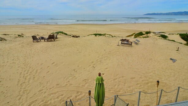 A beach with a fenced area containing lounge chairs and a table. - Magnificent Ocean views! On Oceano sandy beach with fire pit  (Oceano,)