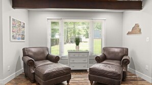 A room with two leather armchairs, a white dresser, and a window with blinds. - USAF VETERAN OWNED - DEEP WATER, HUGE HOME, Fire Pit, WiFi, Kayaks/SUP's! (Huddleston)