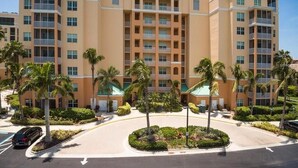 A multi-story hotel with a central courtyard, palm trees, and a clear sky.