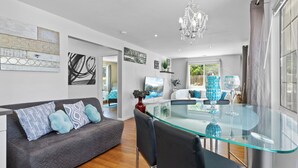 Un salón moderno con una mesa de comedor de cristal, un sofá gris y sillas negras.