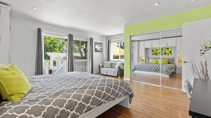Un dormitorio moderno con una cama grande, un ventanal corredero que da a un balcón y vistas al exterior.