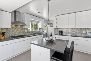 Een moderne keuken met witte kastjes, een centraal eiland en een achterwand met mozaïek tegels.