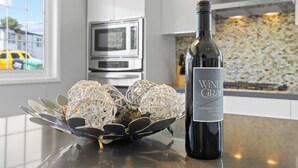 Una cocina con una botella de vino, un cuenco decorativo y un microondas.