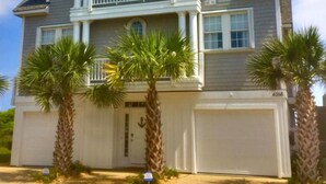 Une maison à deux étages avec un balcon, des palmiers et un garage.