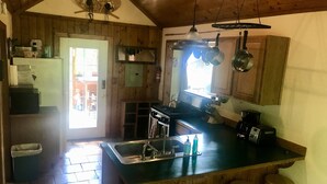 Una cocina rústica con paredes de madera, una isla grande con taburetes, una estufa y lámparas colgantes.
