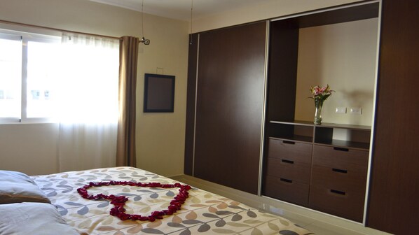 A hotel room with a bed, a wardrobe, a vanity with a mirror, and a window with curtains. - 3 Blocks to the beach, condo with private rooftop, fantastic location. Big pool! (Playa Del Carmen)