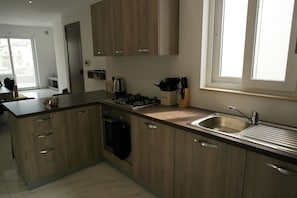 Modern kitchen with oven, gas stove, and stainless steel sink.