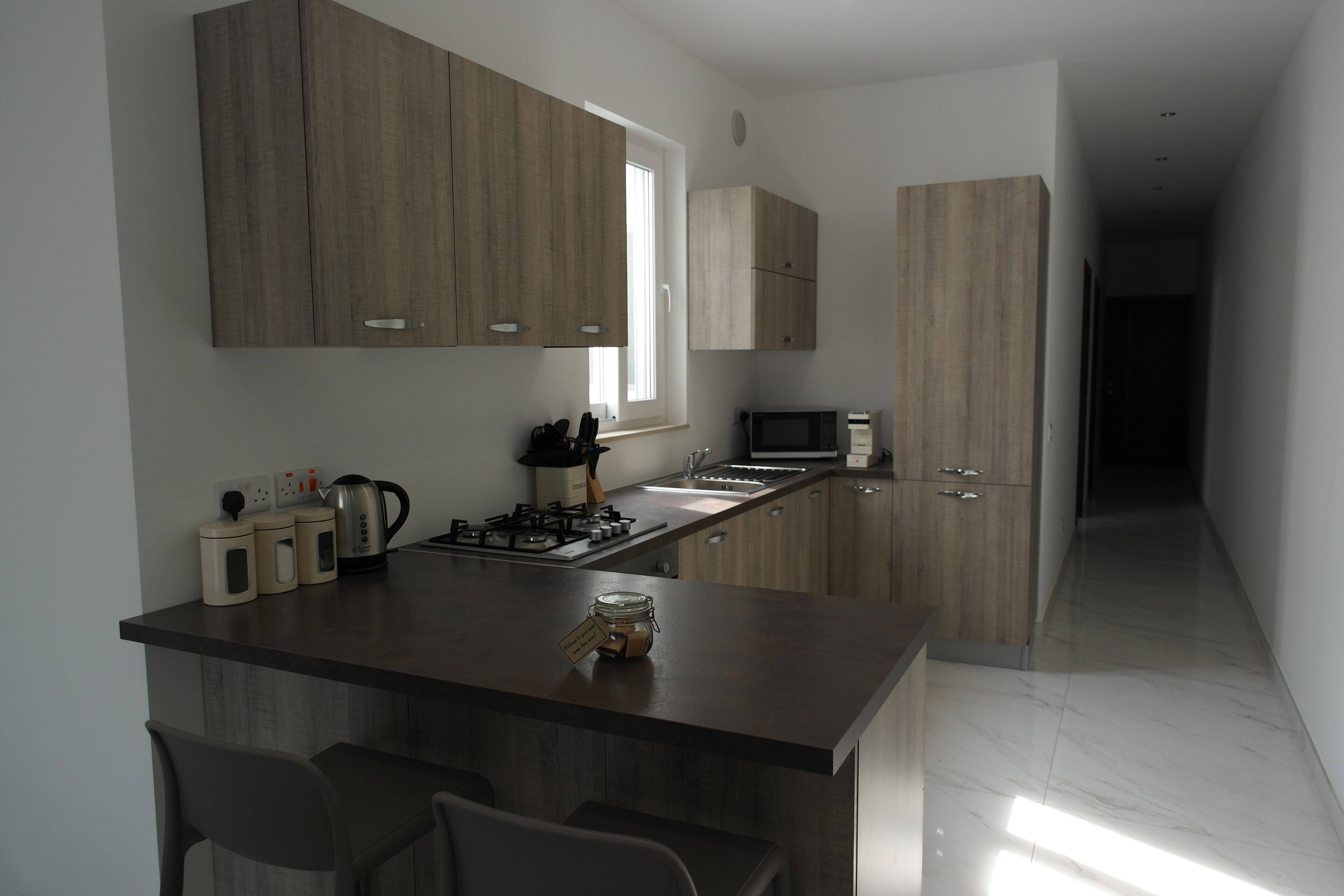 Une cuisine moderne dotée d’un îlot central, d’appareils électroménagers intégrés et de meubles de rangement en bois.
