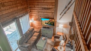 A cozy log cabin interior with a sofa, armchairs, a coffee table, and a TV on a wooden wall. - Stemwinder #3:  3 Bedrooms Plus Bonus Sleeping Loft.  2 Full Baths (Snowshoe)